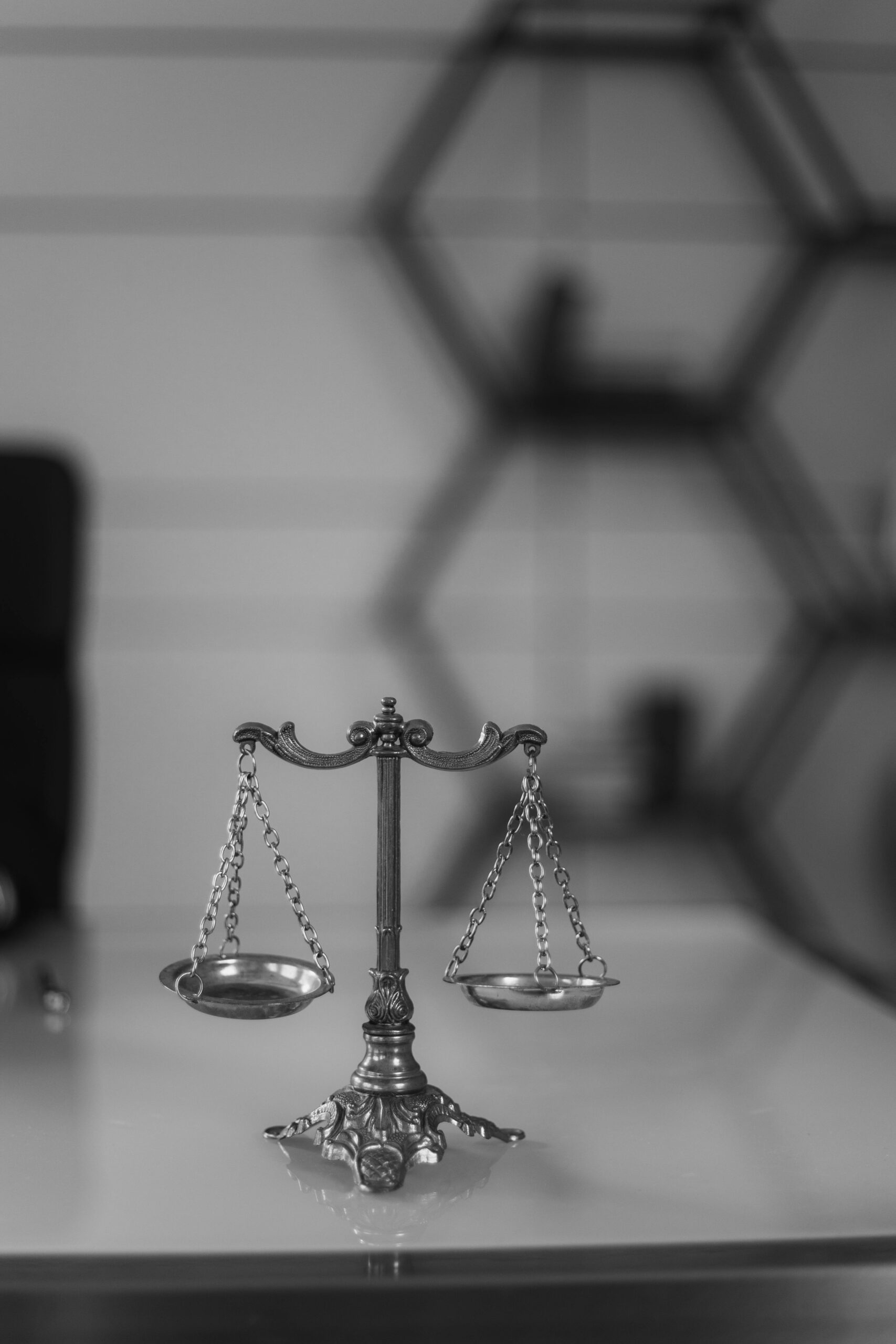 Home A black and white photo of a vintage balance scale in an office environment, emphasizing symmetry and justice.